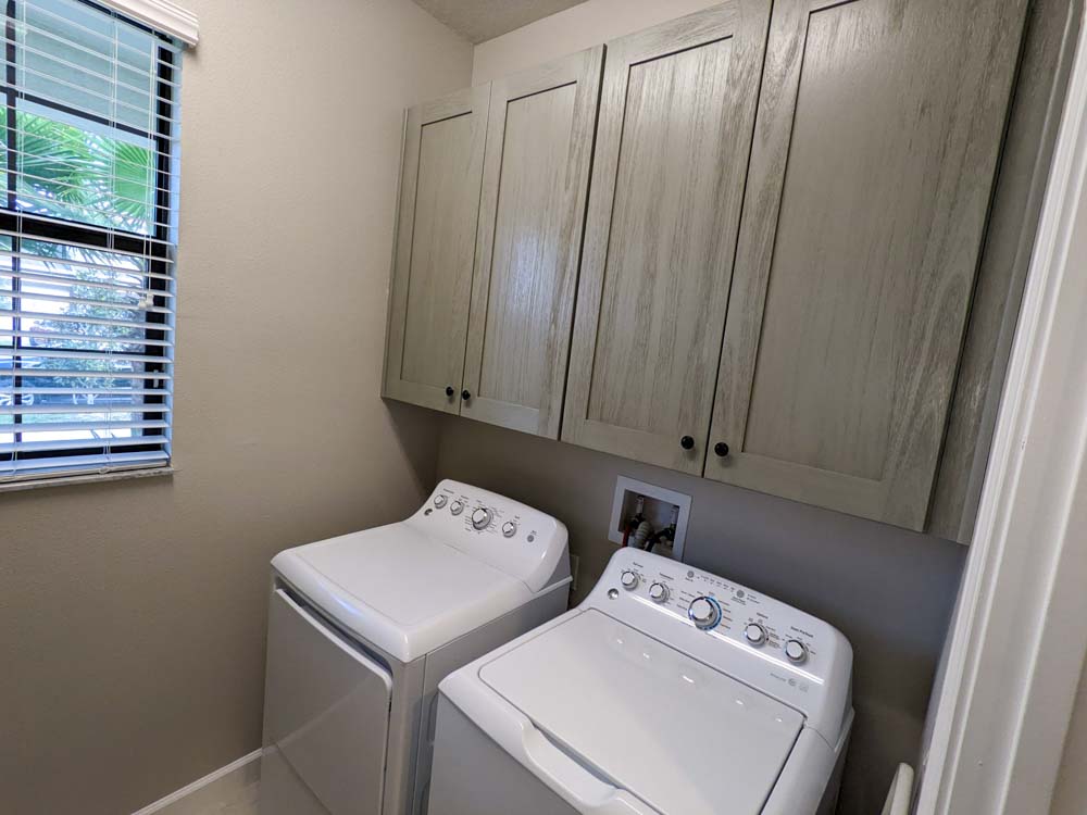 Gray shaker wall cabinets installed above a side-by-side washer and dryer, Trusted Choice Cabinets