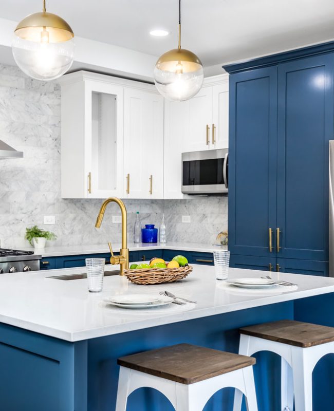 modern luxury kitchen with an island, custom blue colored kitchen cabinets, marble countertops and silver appliance
