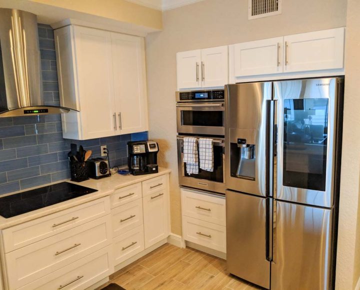 kitchen flat cooktop with silver roof, ice white shaker cabinet doors, offset tile backsplash pattern, and silver appliances