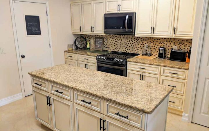 kitchen with an island with a granite countertop, and signature pearl kitchen cabinet doors, black appliances